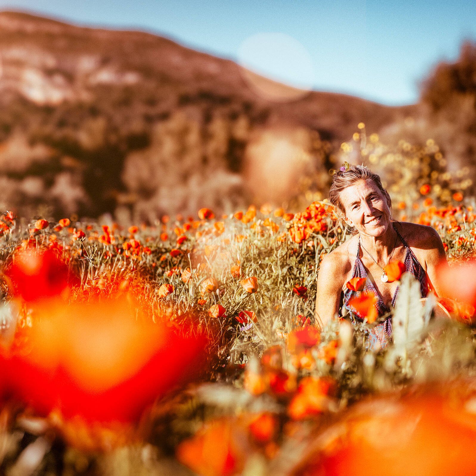 Intuition, Bauchgefühl, weibliche Selbstermächtigung, Frau steht inmitten einem feuerroten Mohnblumenfeld