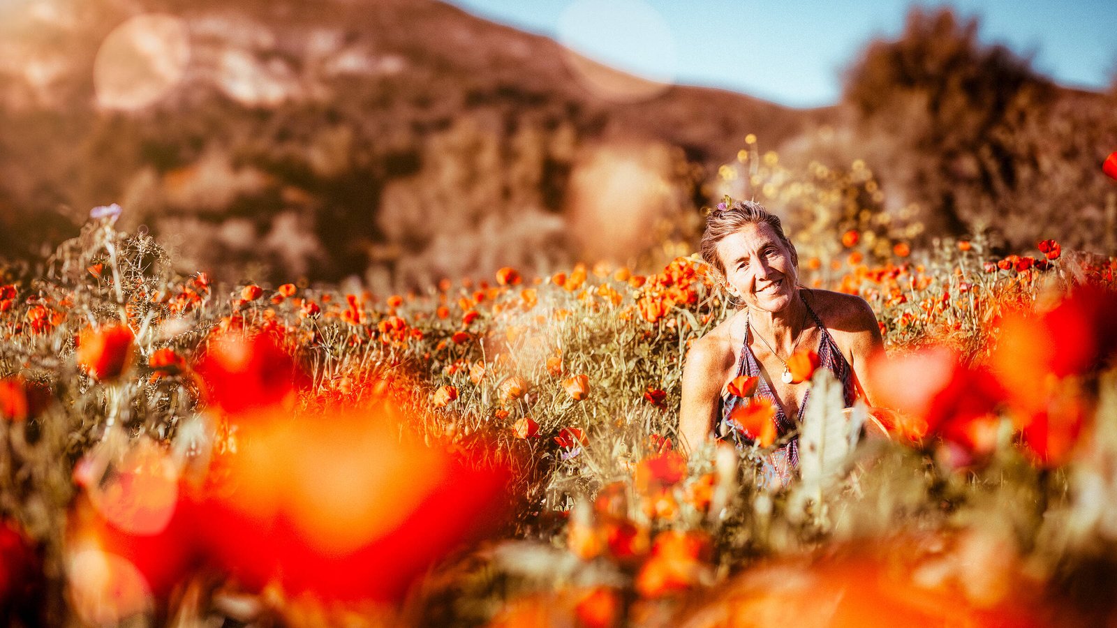 Intuition, Bauchgef&uuml;hl, weibliche Selbsterm&auml;chtigung, Frau steht inmitten einem feuerroten Mohnblumenfeld