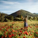 Intuition, Bauchgefühl, weibliche Selbstermächtigung, Frau steht inmitten einem feuerroten Mohnblumenfeld
